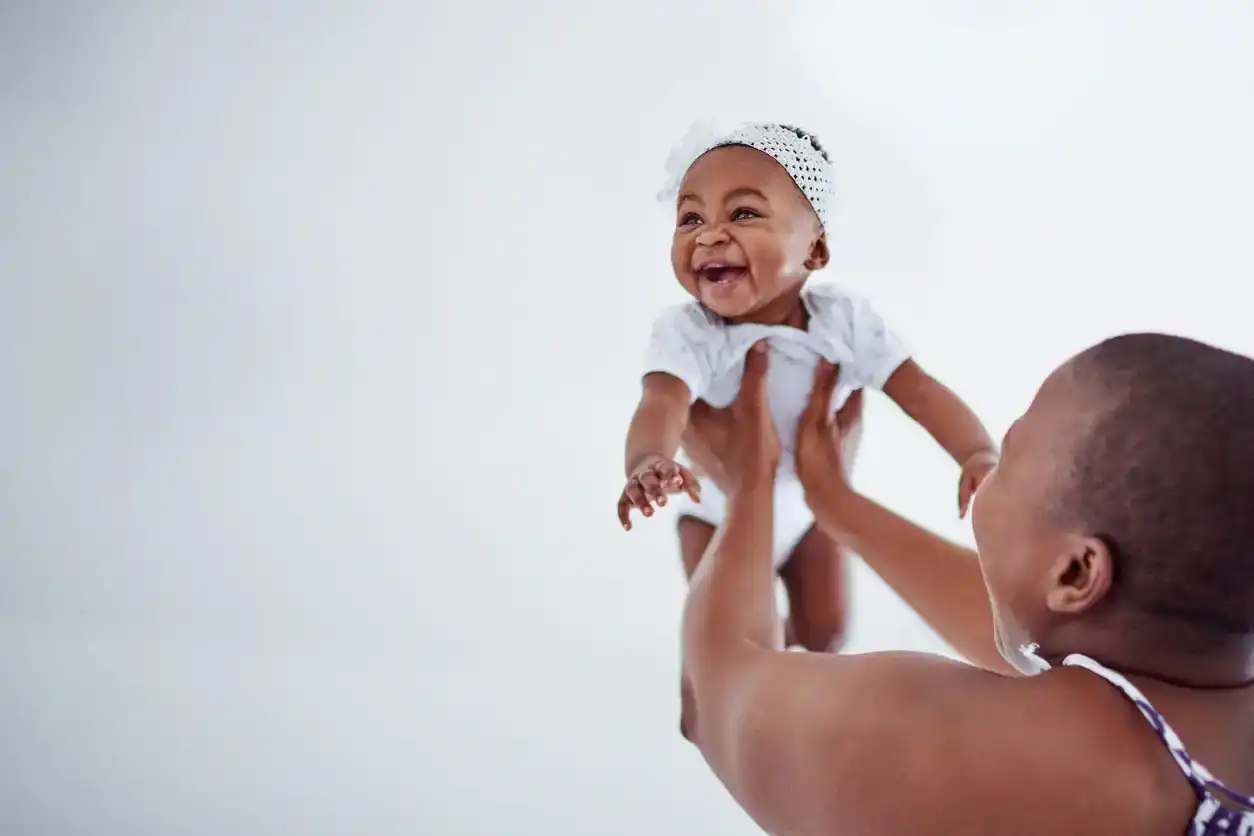 Mother holds happy baby girl in the air. Cute nicknames for girls.