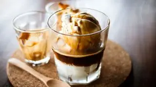 Un affogato dans un verre sur un panneau de liège avec une cuillère en bois