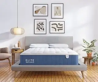 월 아트 아래 흰 벽에 기대어 있는 Bear Elite 하이브리드 매트리스.