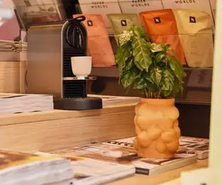 Cafeteira Nespresso sobre uma mesa com revistas ao redor