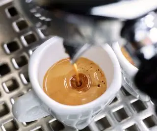 Uma máquina de café expresso preparando uma dose de café em uma caneca branca