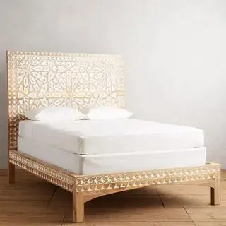 Cama Albaron esculpida à mão contra uma parede cinza.