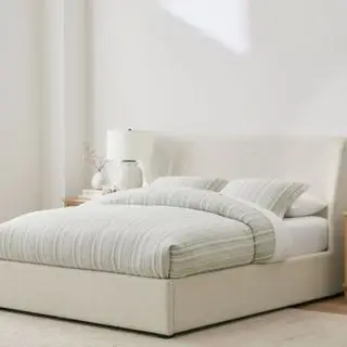 Cama estofada Layton contra uma parede branca.