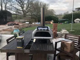 Pridanie dreva do palivového otvoru na zadnej strane Ooni Karu 16, aby sa pomohlo dostať na teplotu