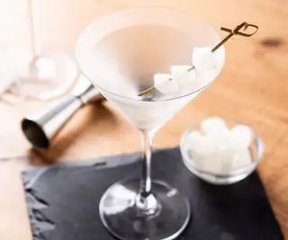 Un verre à martini avec une ardoise et un jigger en arrière-plan