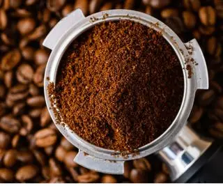 marc de café dans un porte-filtre au-dessus des grains de café