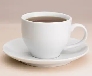 Une tasse à thé et une soucoupe sur une surface rose pâle