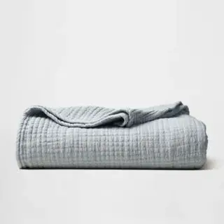 Couvre-lit en mousseline sur fond gris.