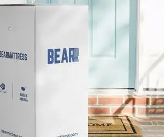 Matelas ours dans une boîte devant une porte d’entrée bleu clair.