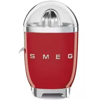 Un mini presse-agrumes Magic Bullet sur fond blanc avec une tasse pleine de jus d'orange et son outil de nettoyage.