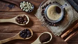 cuillères de grains de café dans différentes torréfactions autour d'une tasse de café