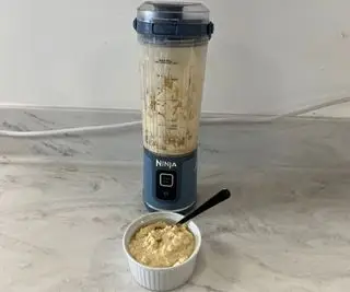 Un'immagine per la stampa dell'esplosione Ninja piena di frutta in una cucina moderna. Dietro c'è un tagliere di legno con frutta tagliata