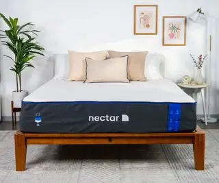 Un matelas Nectar sur un lit avec des oreillers contre un mur blanc de la chambre.