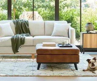 정원 전망을 감상할 수 있는 창문과 발판이 있는 흰색 소파.