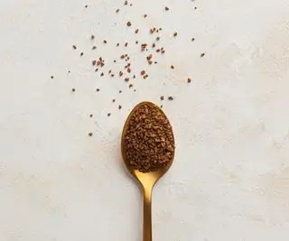 Goldener Teelöffel mit Instantkaffee darauf und etwas auf der Arbeitsplatte verstreut