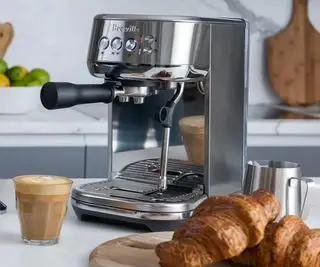 Breville Bambino Plus sur un comptoir avec des croissants et un café devant