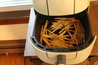 Belle friteuse à air numérique de 6 litres à côté d'un bol de frites fraîches