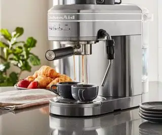 Machine à expresso KitchenAid en gris sur un comptoir tirant des shots d'espresso dans deux tasses