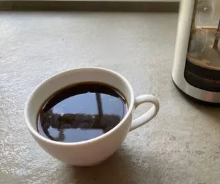 Une tasse de café dans une tasse blanche devant la presse française OXO