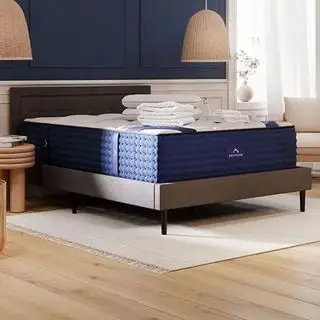Un matelas hybride de luxe DreamCloud sur un lit gris dans une chambre