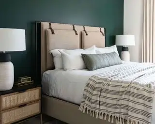 Chambre moderne avec mur vert forêt et tête de lit beige avec lampes blanches