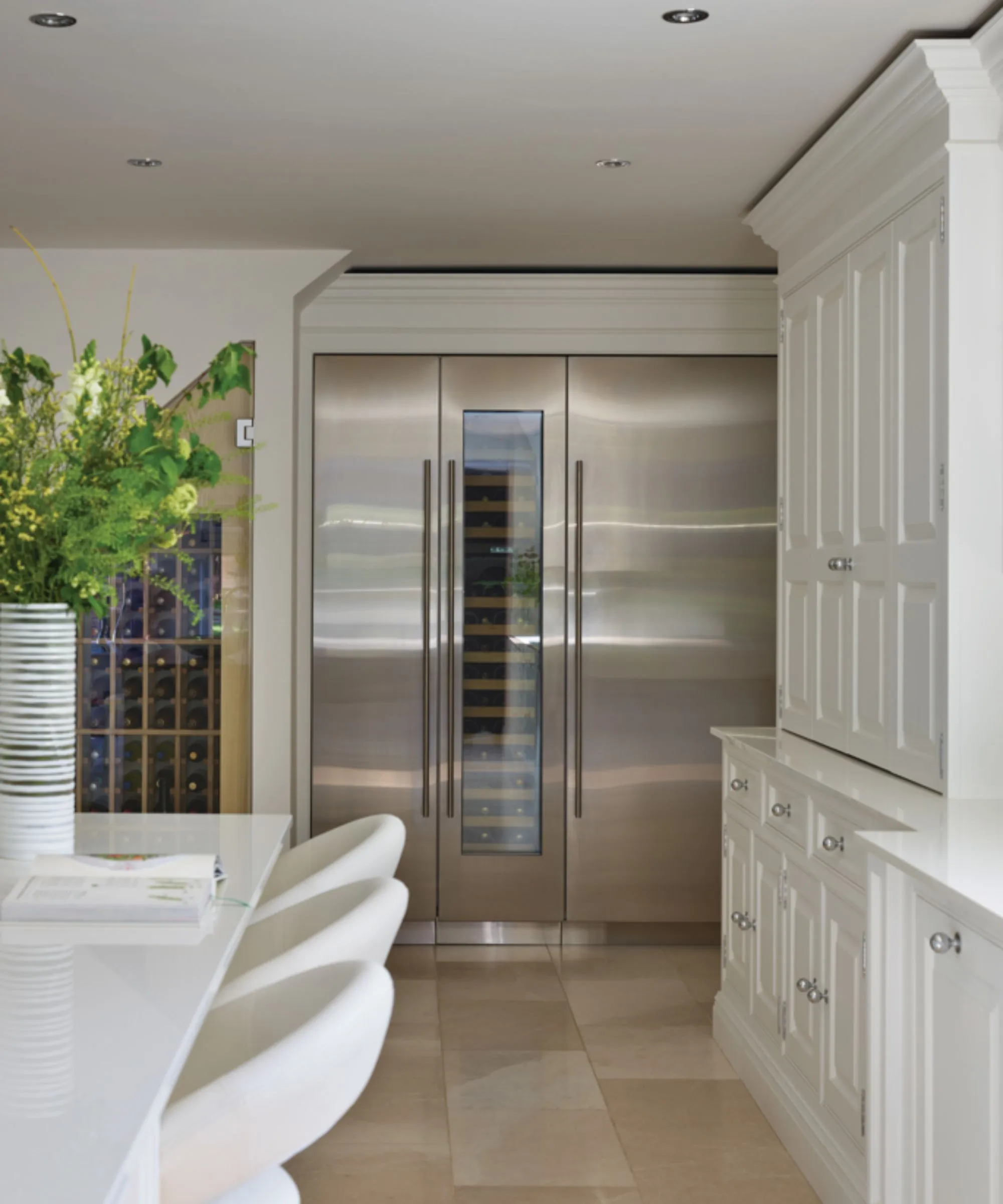 Frigoríficos altos y plateados empotrados en una cocina con una ventana para vino que muestra el interior.' loading='lazy' title=