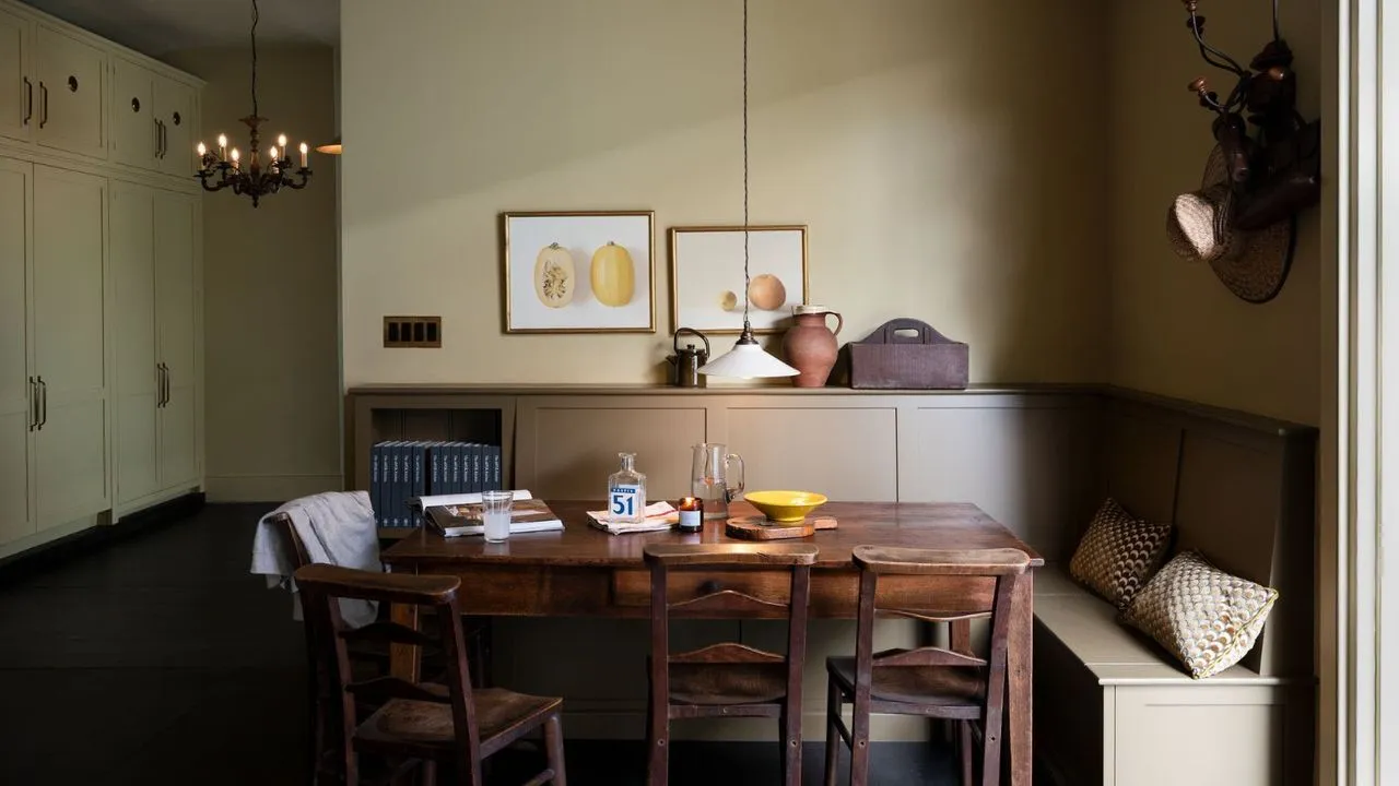 Jedálenský kút svetlohnedej farby so vstavanými lavicami v tvare L v tmavom tmavom tmavom tmavom lakovanom drevenom stole z polovice storočia so štyrmi jedálenskými stoličkami a vstavanou skriňou od podlahy až po strop vľavo' loading='lazy' title=