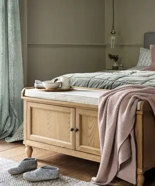 Un banc de rangement avec portes d'armoire et un dessus de coussin au bout d'un lit