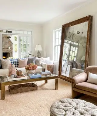 Grand miroir antique dans le salon avec tapis neutre et table basse ornée de fleurs, de livres et de décoration