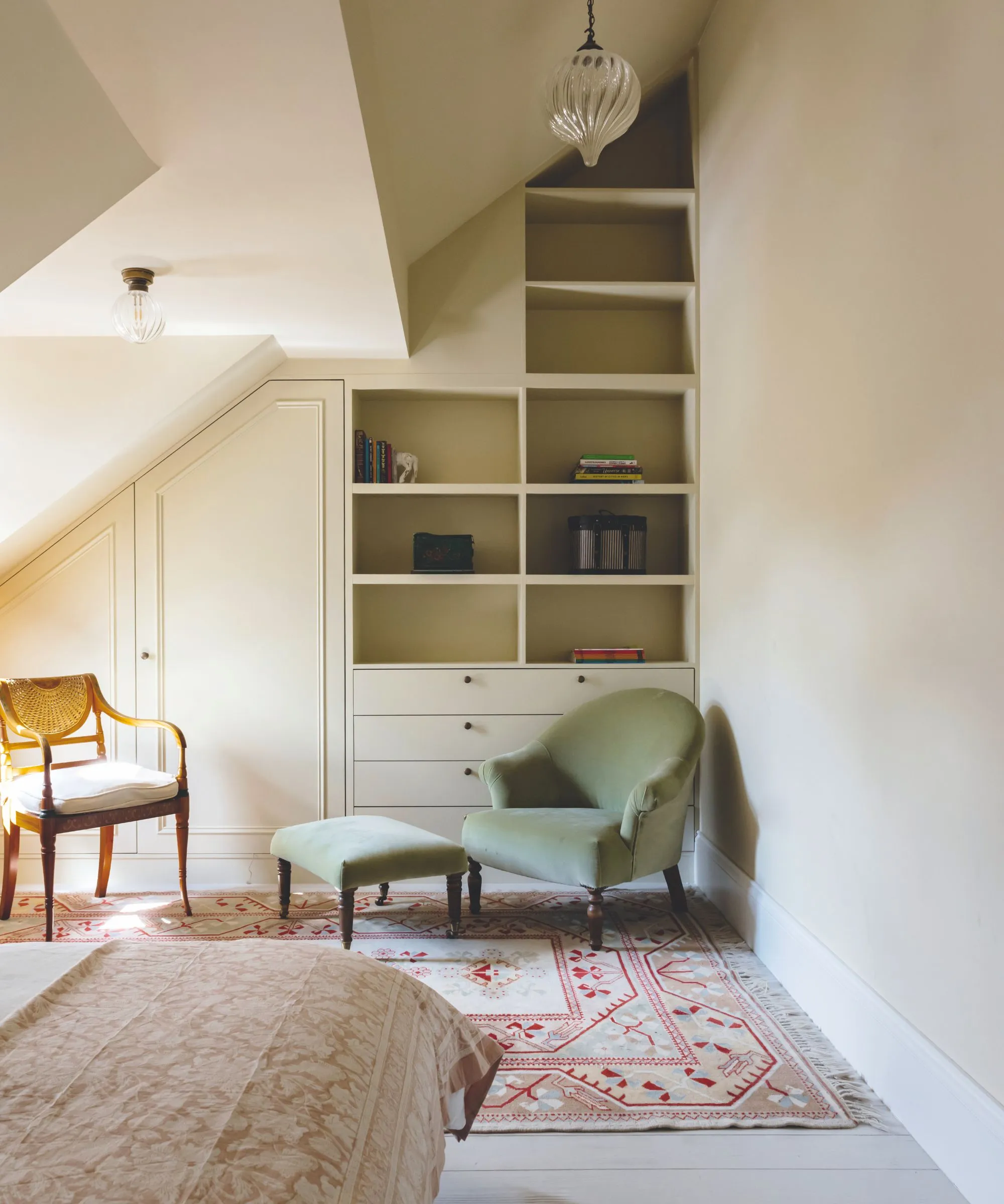 Podkrovní ložnice s vestavěnými policemi a skříněmi pouze na zadní stěně.' loading='lazy' title=