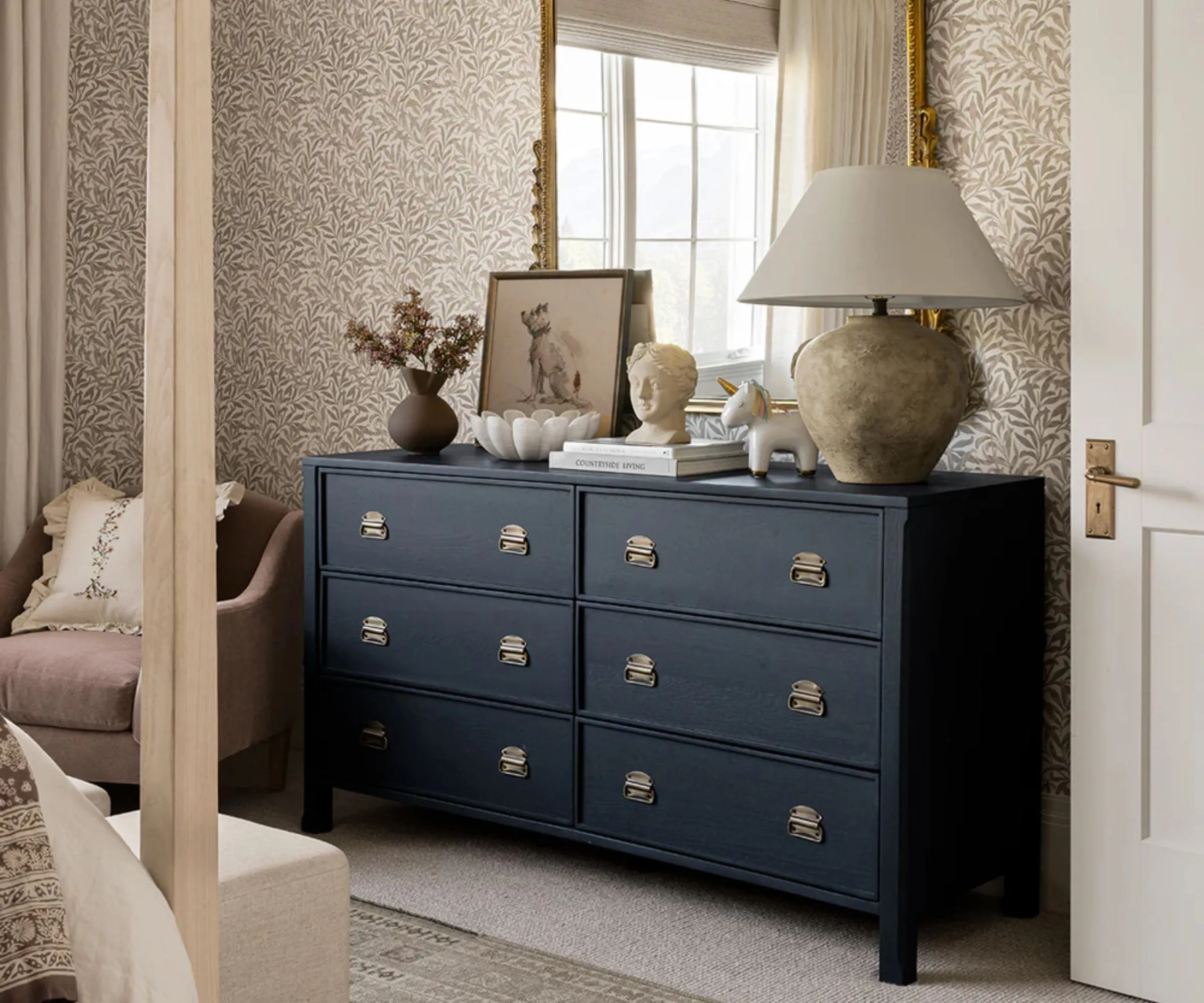 Una cassettiera a 6 cassetti dipinta di blu scuro in una camera da letto.' loading='lazy' title=