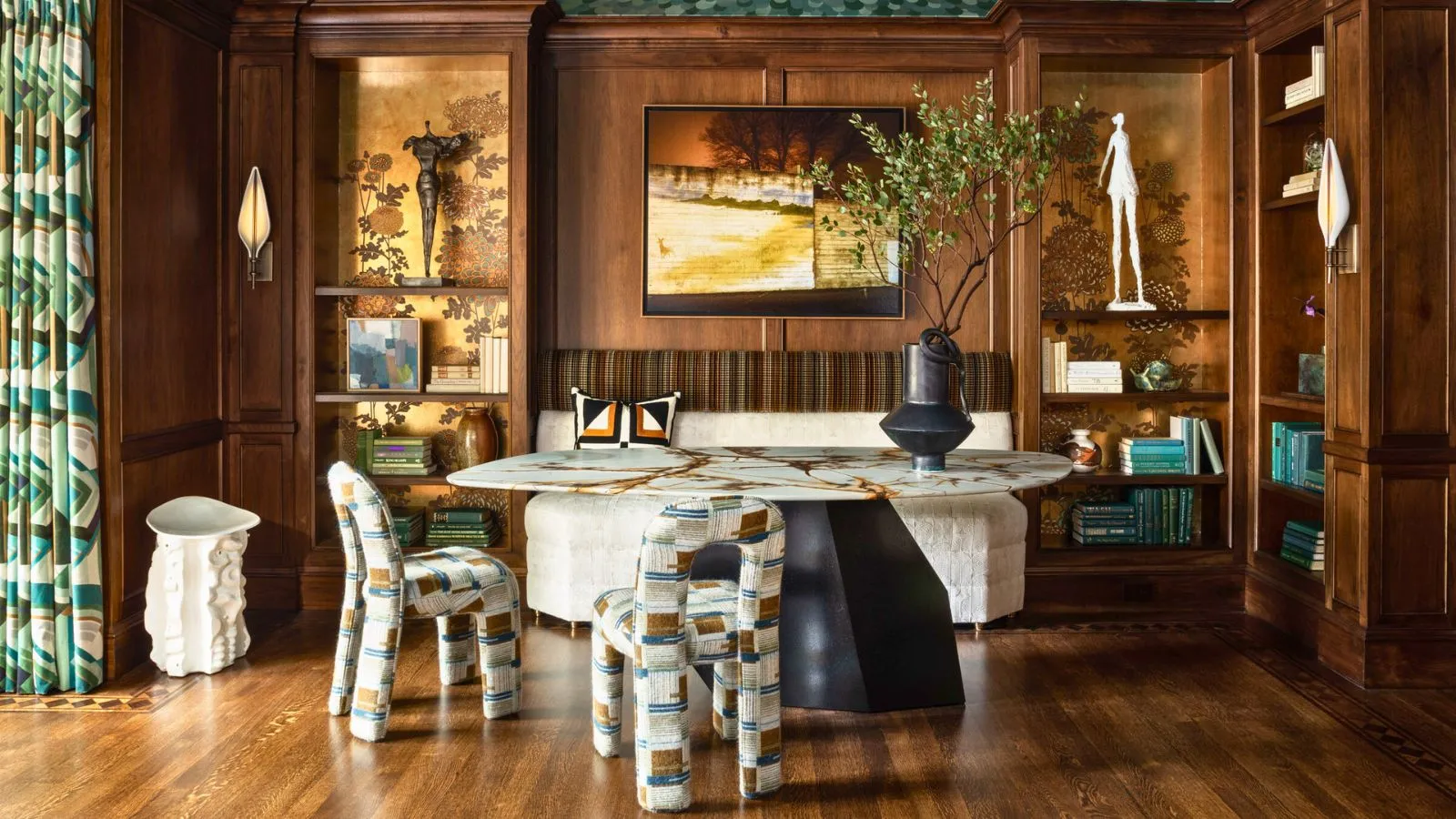 Jadalnia z wbudowanymi drewnianymi półkami i wnękami z błyszczącymi, metalicznymi krzesłami z tapetą Fromental i pomysłowym wystrojem' loading='lazy' title=