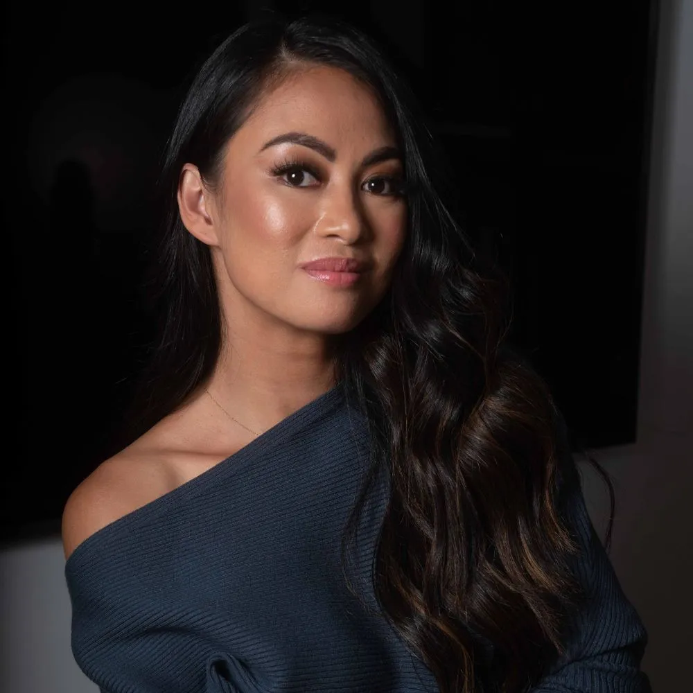 Zdjęcie Rechelle Balanzat w ciemnej granatowej bluzce z odkrytymi ramionami na czarnym tle' loading='lazy' title=