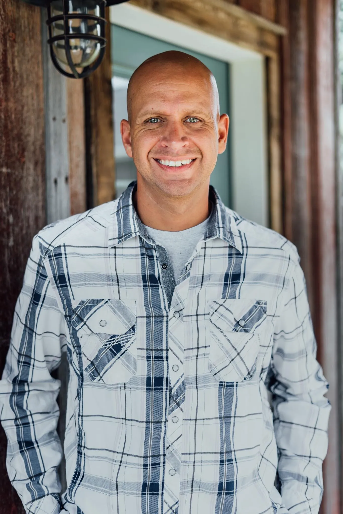 Dan ist ein Mann, der ein Kragen -Check -Hemd trägt, das auf einer hölzernen Veranda steht' loading='lazy' title=
