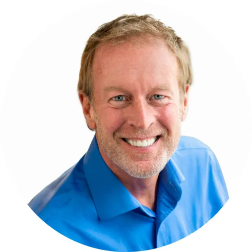 Robert ist ein weißer Mann, der ein Hemd mit blauem Kragen trägt und gegen einen weißen Hintergrund in die Kamera lächelt' loading='lazy' title=