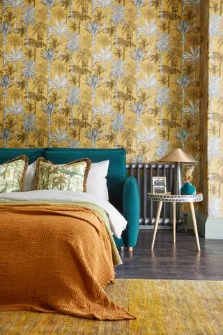 Canapé-lit prolongé en lit dans une chambre avec parquet et papier peint à motifs