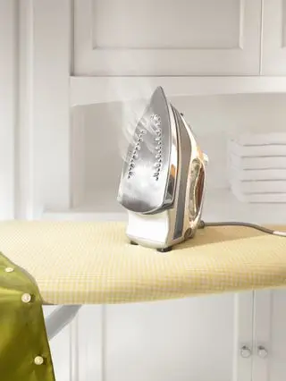 Un ferro fumante su un asse da stiro giallo