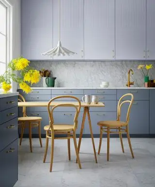 Armoires grises, chaises et table jaunes, suspension blanche