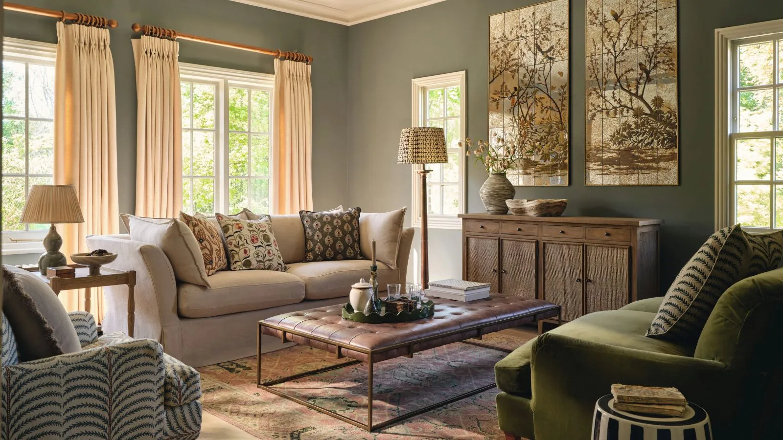 Ein grünes Leben mit einem cremefarbenen Zweisitz-Sofa, ein grünes Sofa gegenüber und ein Couchtisch aus Leder in der Mitte.' loading='lazy' title=