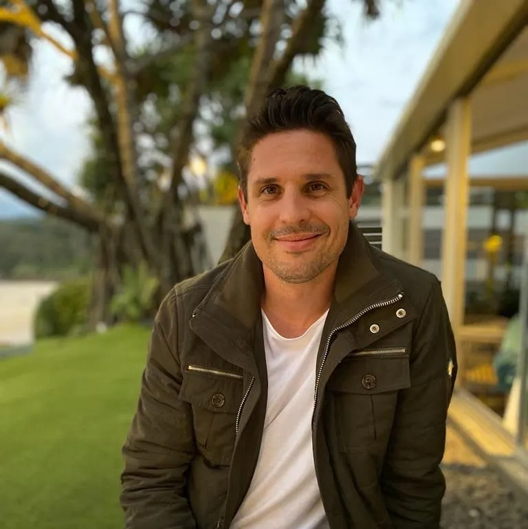 Zdjęcie profilowe Josha Mitchella na słonecznym podwórku z palmami na niewyraźnym tle' loading='lazy' title=