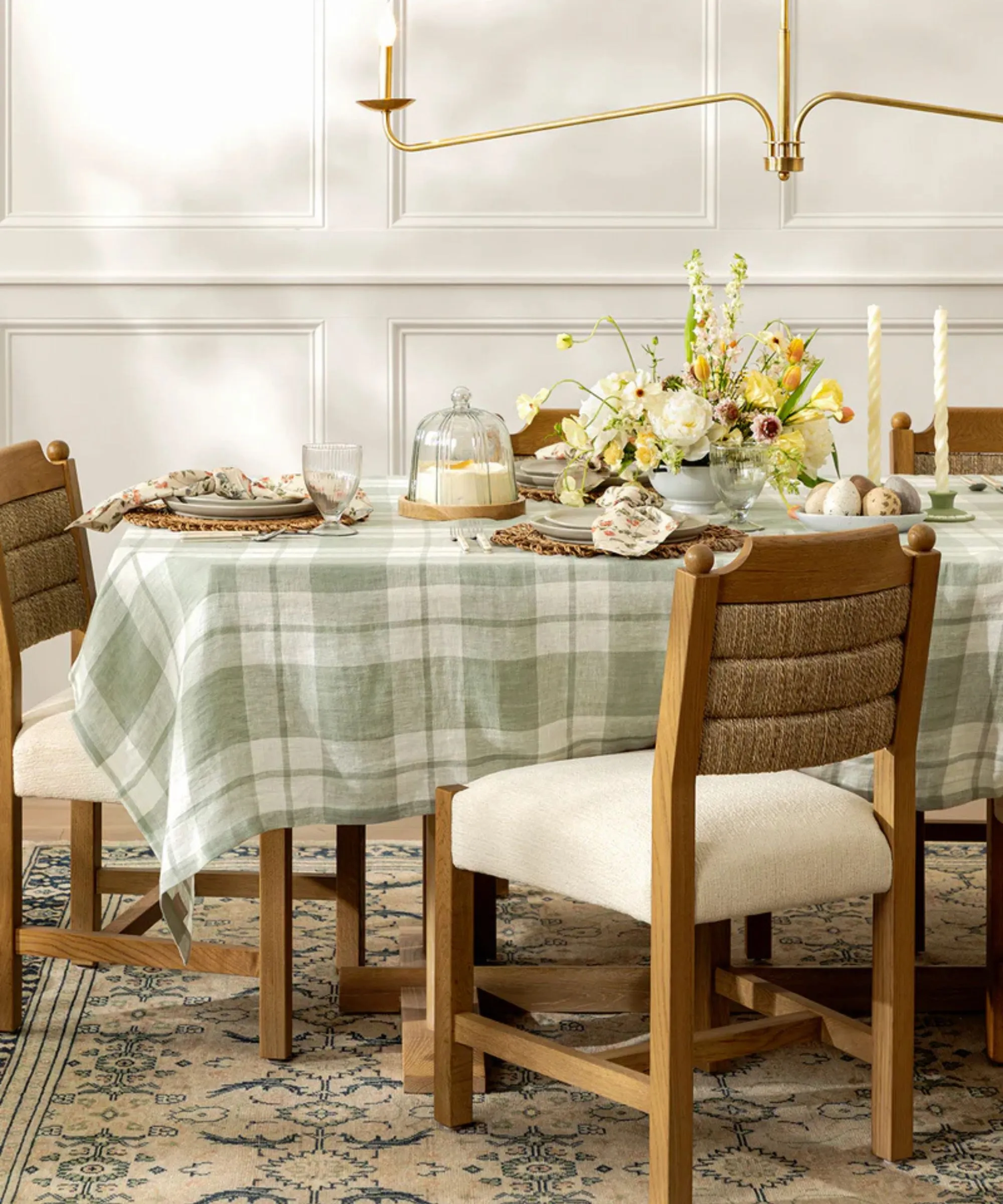 Una mesa de Pascua decorada con un mantel de cuadros azul claro y vajilla a juego.' loading='lazy' title=