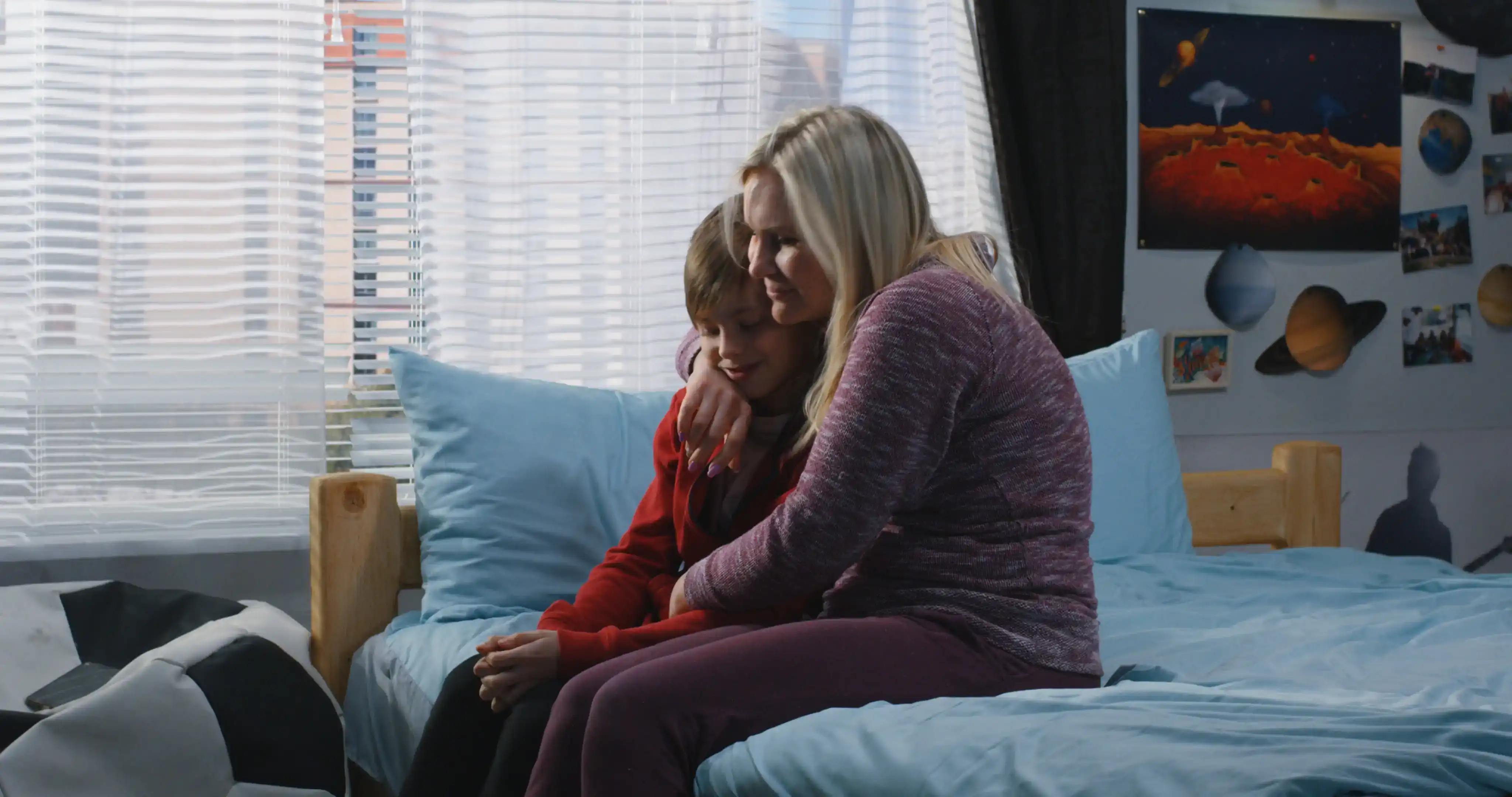 Medium shot of a mother talking with and hugging her son while sitting on a bed